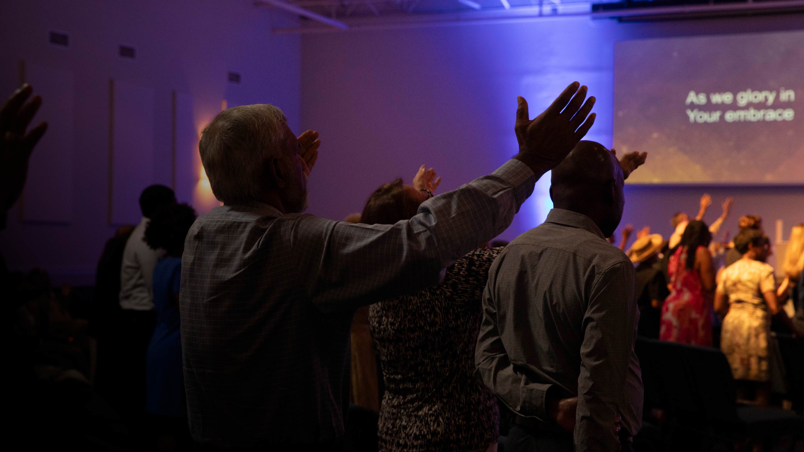 Church family worshipping with hands raised